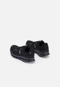 Schwarze Sportschuhe mit einem Obermaterial aus Mesh, auffälligem Logo und gepolsterter Sohle mit einem einzigartigen segmentierten Design für Flexibilität.