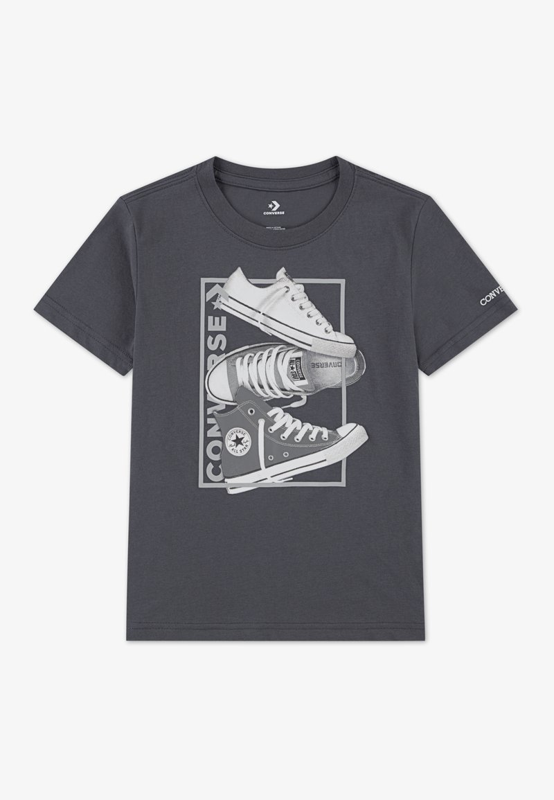 Grå T-shirt med en grafisk design av klassiska Converse-sneakers i vitt och grått, med detaljerade skosnören och branding.
