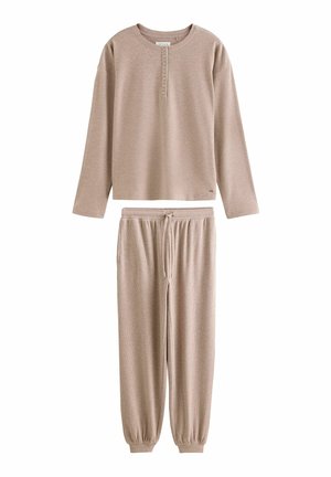 Camiseta henley de manga larga beige con botones combinada con pantalones jogger a juego con cordón y puños elásticos.