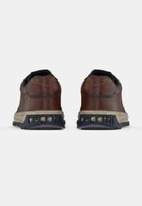 Pruunid nahast tennised tekstuurse viimistlusega, millel on must kummist tald ja kandjal bränditud detailid.