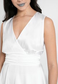 Weißes Satin-Kleid mit tiefem V-Ausschnitt, ärmellosem Design und gerafftem Taillendetail. Glatte Textur und fließender Rock.