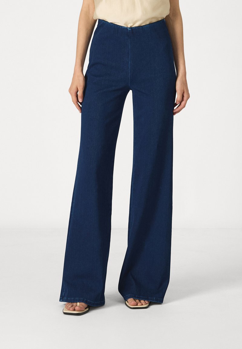 Dark blue high-waisted denim trousers with a wide-leg design. Smooth texture, minimal seams, and no visible embellishments.