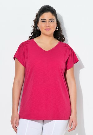 T-shirt fuchsia à col en V avec des manches courtes, présentant des détails texturés sur les épaules. Tissu doux avec une coupe décontractée et sans motifs.