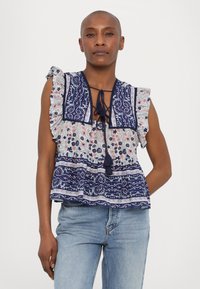 Top sin mangas de flores y estampado en tonos de azul y blanco, con hombros con volantes y un escote atado con borlas.