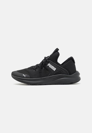 Sapatos atléticos pretos com parte superior em rede, colarinho acolchoado e sola de borracha. O design inclui atacadores e um logótipo branco na lateral.