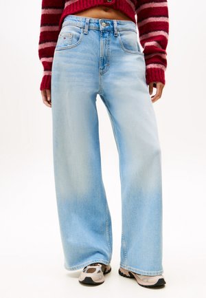 Lyseblå jeans med vide ben, båret med beige og brune sneakers og en rødstribet cropped sweater, vist fra mave til fødder.