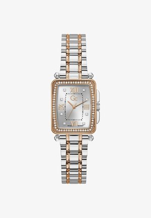 Kuld- ja hõbemetallist kell ristkülikukujulise näo, teemanditükkide, rooma numbrite ja hõbedase dialiga. Omab kahetoonilist rihma.