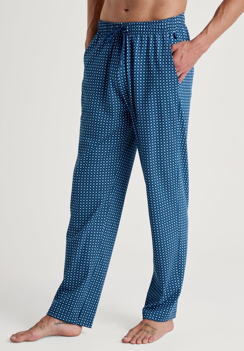 Mannelijke blauwe pyjamabroeken met een geometrisch patroon van witte stippen, elastische tailleband met trekkoord en zijzakken. Zachte, lichte stof.
