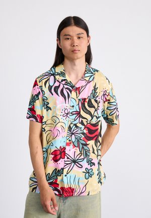 Camisa de botón de manga corta en colores pastel; presenta un patrón floral en rojo, azul y negro sobre un fondo beige. Bolsillo en el pecho izquierdo.