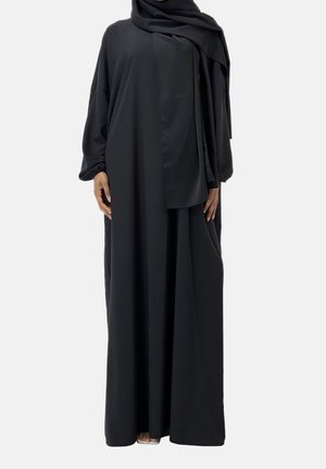 Robe noire longue et fluide en tissu doux avec des manches larges et un foulard assorti, présentant un design minimaliste et une silhouette drapée.