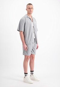 Grijze short-sleeve shirt en bijpassende shorts hebben een gestructureerd, geruit patroon. Draag het met witte sneakers en zwart met patroon sokken.