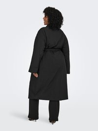 Svart lång kappa med skärp i midjan, långa ärmar och en ren design. Tillverkad av ett slätt tyg med mjuk textur, utan synliga mönster.