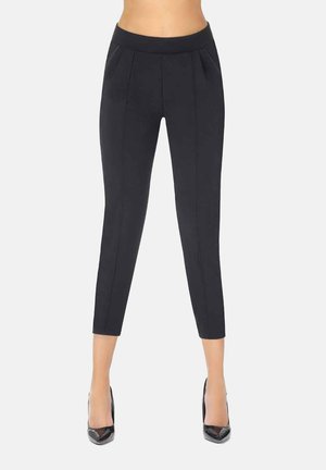 Czarne spodnie cropped z elastycznego materiału o dopasowanym kroju, z przodu fałdami i bocznymi kieszeniami, w połączeniu z butami na wysokim obcasie.