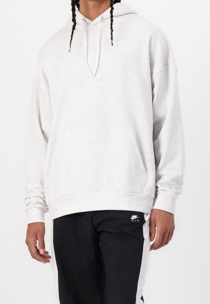 Sudadera gris clara de tela suave, que incluye un bolsillo frontal, capucha con cordón ajustable y un pequeño logo en el pecho.