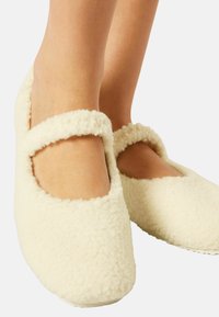 Cremfarbene, flauschige Hausschuhe mit abgerundetem Zehenbereich und weichem, strukturiertem Obermaterial. Verfügen über ein abgerundetes Ausschnitt-Design um den Knöchel.