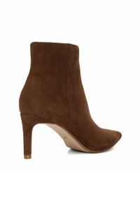 Bottine en daim marron avec un talon aiguille effilé, une pointe fine et un minimum de coutures, présentant une texture lisse et un design épuré.