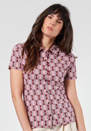 Kurzarmhemd mit einem pinken und burgunderfarbenen Kreismuster, mit einer Knopfleiste vorne und einem Kragen, der mit einem kleinen Logo versehen ist.