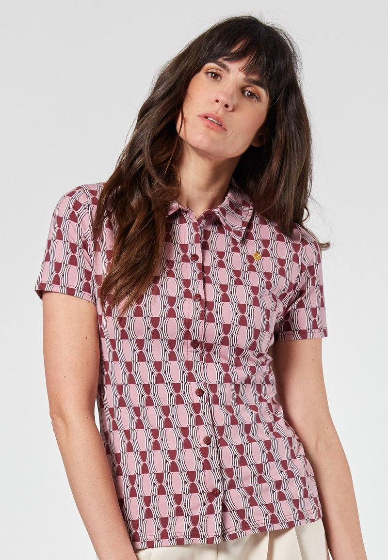 Camicia a maniche corte con un motivo circolare in rosa e bordeaux, dotata di chiusura con bottoni e colletto, con un piccolo dettaglio del logo.
