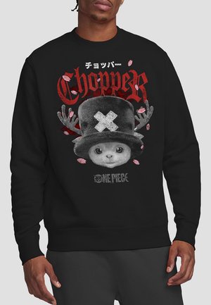 Black sweatshirt featuring a graphic print of a cartoon character with antlers, text reading "Chopper," and floral accents in pink.