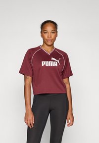Burgundy short-sleeved athletic top made of lightweight fabric features a v-neck and white PUMA logo, with contrasting white stitching accents.