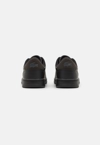 Sneakers neri con tomaia in pelle liscia, collare imbottito e suola in gomma. Presentano un logo embossato sul tallone e dettagli testurizzati.