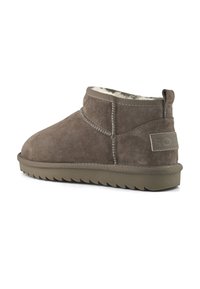 Bota de tobillo de ante marrón con forro de felpa blanca, suela de goma texturizada y tira en la parte posterior.