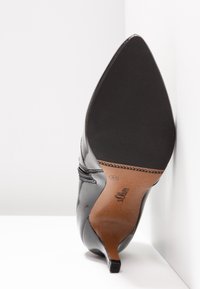 Chaussure à talon haut pour femme en cuir verni noir à bout pointu, semelle visible avec grip texturé et nom de marque s.Oliver, pointure 37.