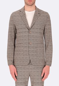 Blazer marrone a fantasia con due bottoni, rever a punta e tasche frontali; realizzato in tessuto testurizzato. Indossato sopra una camicia bianca.