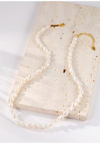 Collar de perlas con perlas blancas de forma irregular, un cierre de oro y una cadena de extensión dorada para ajustar la longitud.