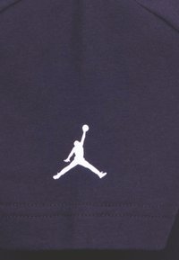 Navy-kangas, jossa on sileä pinta ja valkoinen Jumpman-logo. Suunnittelu on minimalistinen, kontrastiväreillä ja yksityiskohtaisellaommella.