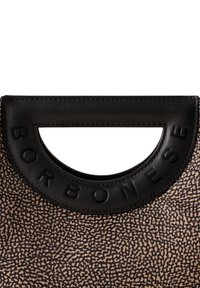 Schwarzer Griff mit Ausschnitten und geprägt ein Branding, angebracht an einer strukturierten beigen Tasche mit einem Punktemuster. Das Material scheint aus Kunstleder zu sein.