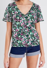Blusenshirt mit kurzen Ärmeln und V-Ausschnitt, mit schwarzem Hintergrund und mehrfarbigen Blättern und Blumen in Grün, Pink und Creme.
