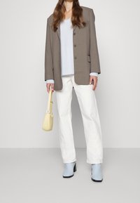 Grå blazern, ljusblå tröja, vita vida byxor, blå ankelstövlar och en liten gul handväska. Har knappar och en texturerad stickning.