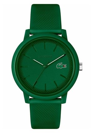 Reloj de silicona verde con correa texturizada, cara redonda minimalista, logo en relieve y marcadores de horas simples. Presenta manecillas y acentos plateados.