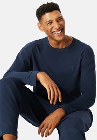 Navyblaue Langarm-Sweatshirt aus weichem Stoff, mit Rundhalsausschnitt und besticktem Logo auf der Brust. Bequemer Schnitt.