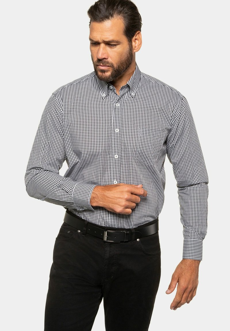 Herre skjorte med knapper lavet af sort og hvidt gingham ternet stof, lange ærmer, button-down krave, parret med et sort bælte og mørke jeans.