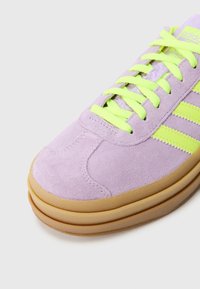 Violeta gamuza sporta kurpe ar neona zaļām šņorēm un strīpām, apaļiem purngaliem un teksturētu gumijas zoli.