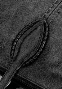 Dettaglio di una borsa in pelle nera caratterizzata da una superficie texturizzata, accenti in pelle intrecciata e una chiusura con zip con cuciture visibili.