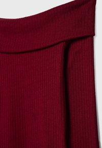 Haut bordeaux côtelé à épaules dénudées avec un col replié, présentant une texture lisse et une coupe ajustée.