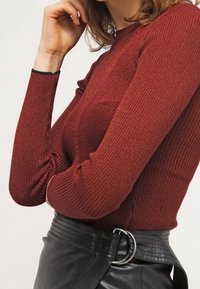 Stickad bourgogne långärmad topp med ribbad textur, skräddarsydd design och framhävda axlar, matchad med en svart läderskjort med en cirkulär spänne.