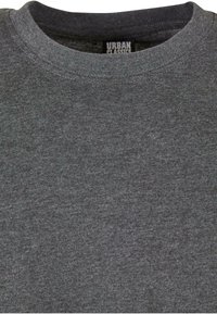 T-shirt grigia a girocollo realizzata in morbido cotone. Design semplice, senza motivi, con un'etichetta sul collo. Texture liscia.