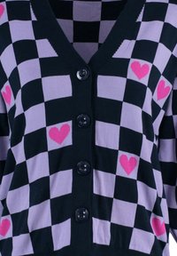 Sweter wykonany na drutach z czarno-lawendowym wzorem w kratkę i różowymi serduszkami. Projekt z dekoltem w serek oraz cztery czarne guziki z przodu.