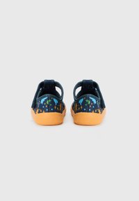 Chaussures en tissu bleu avec une semelle en caoutchouc orange, ornées d'un motif d'animaux colorés et de feuillage. Design léger avec une languette à l'arrière pour un enfilage facile.
