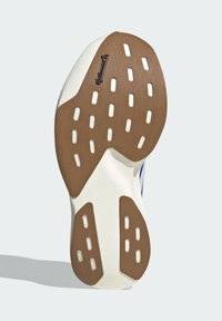 Semelle de chaussure avec des sections de grip en caoutchouc blanc et brun, présentant des découpes rectangulaires et un logo Continental près de la zone des orteils.