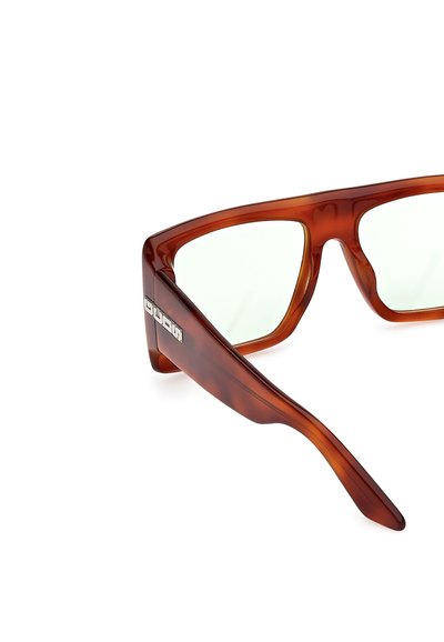 Gafas de sol de carey marrón con montura angular y lentes verde claro, con un logo plateado en la patilla. Textura suave, material duradero.