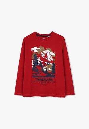 Rood shirt met lange mouwen met een berg-, bomen- en huttenafbeelding en de tekst "Timberland Built to Withstand the Elements Est. 1973" aan de voorkant.