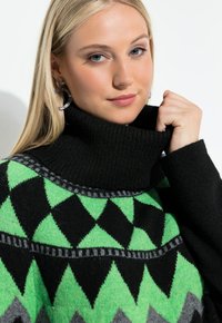 Čern�ý rolák se zelenými a šedými geometrickými vzory. Textura vypadá jemně; má žebrovaný límec a výrazné trojúhelníkové vzory.