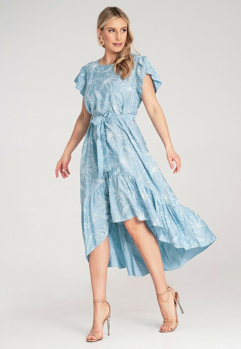 Niebieska sukienka w białe kwiatowe wzory, z krótkimi falbaniastymi rękawami, talią podkreśloną paskiem i asymetrycznym dołem. Gładki materiał o lekkiej teksturze.