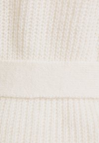 Sweter w kolorze kremowym z dzianiny, charakteryzujący się teksturowanym wzorem, miękkim materiałem oraz gładkim, szerokim pasem w talii dla lepszej struktury.