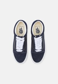 Mornarske suede tenisice s bijelim vezicama, klasičnog dizajna, bijela gumena potplata i Vans logo na jeziku. Imaju dekorativno šivanje.